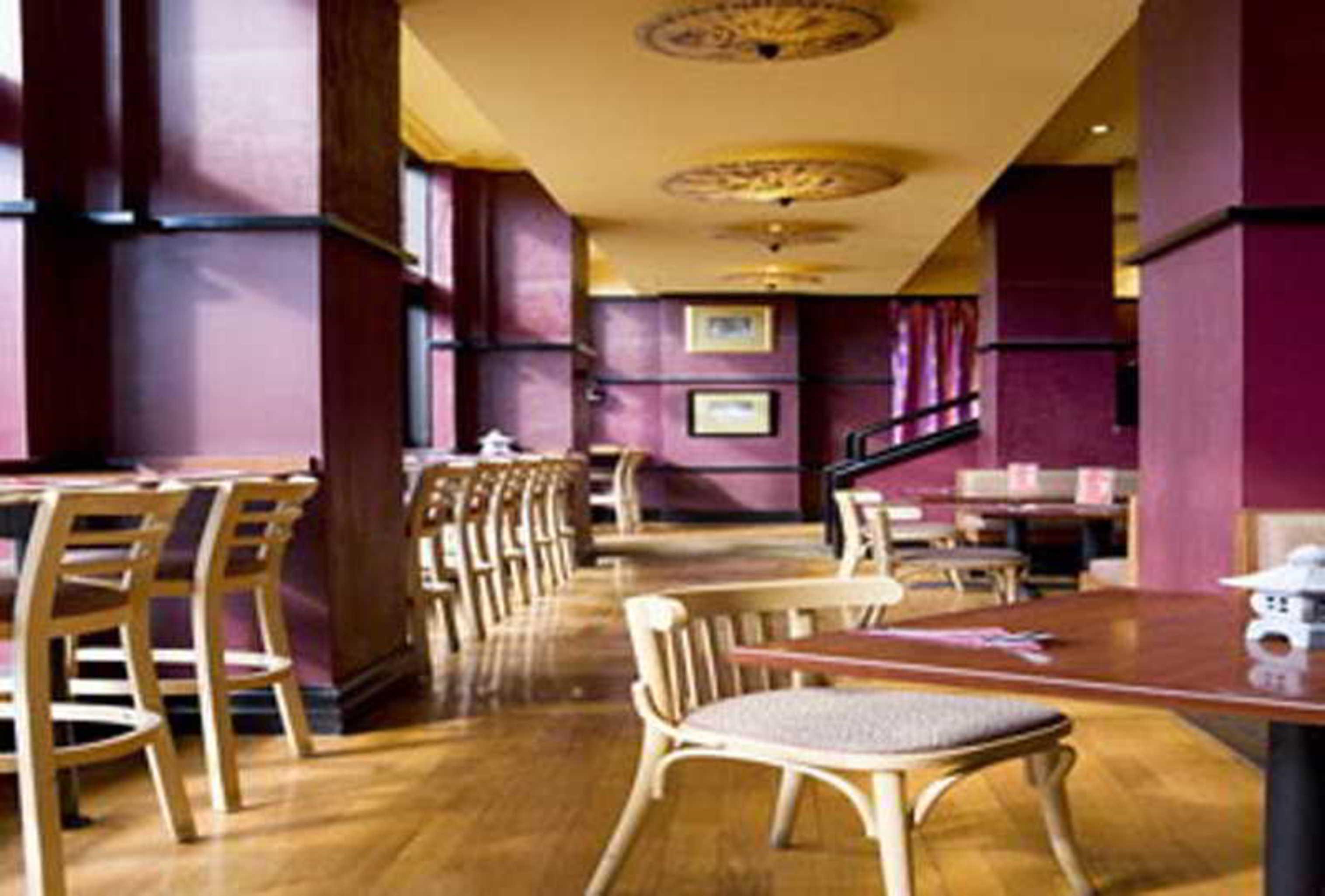 Отель Stamford Grand Adelaide Гленелг Экстерьер фото The photo shows the interior of a restaurant. It features wooden flooring and a warm color palette, primarily using shades of burgundy and gold. There are several wooden chairs arranged around tables, with the seating area appearing spacious and invi